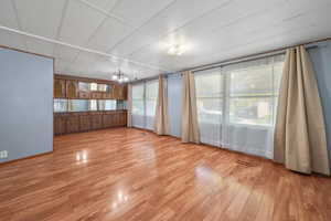 Unfurnished room with a chandelier, light wood-type flooring, and visible vents