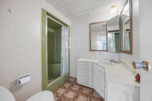 Bathroom with toilet, vanity, and a shower stall