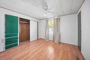 Unfurnished bedroom with a closet, a textured ceiling, ceiling fan, visible vents, and wood finished floors