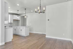Kitchen featuring a chandelier, light wood finished floors, light countertops, baseboards, and recessed lighting