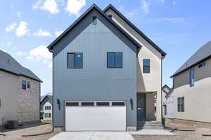 View of front of home featuring cooling unit, driveway, and a garage