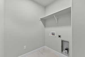 Washroom featuring washer hookup, electric dryer hookup, light marble finish floors, and baseboards