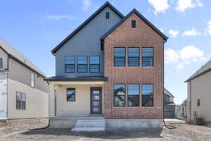 View of front of house featuring board and batten siding, central AC, and brick siding