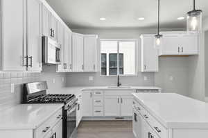 Kitchen featuring appliances with stainless steel finishes, a sink, recessed lighting, light wood-style flooring, and decorative backsplash