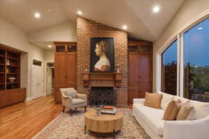 Living room with a brick fireplace, hardwood, recessed lighting, and vaulted ceiling