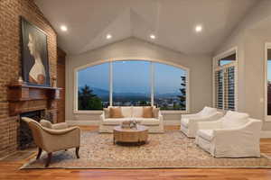 Living area featuring vaulted ceiling, recessed lighting, a brick fireplace, and hardwood floors