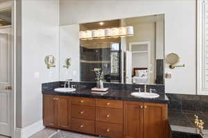Bathroom featuring double vanity, ensuite bathroom, a shower stall, and a sink