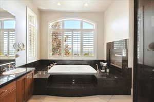 Bathroom featuring a bath, vanity, and plenty of natural light