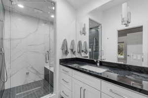 Bathroom with vanity and a marble finish shower