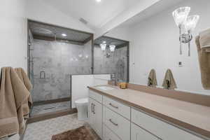 Bathroom featuring lofted ceiling, toilet, visible vents, a shower stall, and vanity