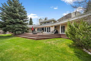 Back of house featuring a chimney, a yard, french doors, a shingled roof, and a deck