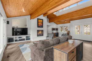 Living area with a lit fireplace, lofted ceiling with skylight, wood ceiling, and visible vents