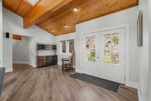 Entryway with wood ceiling, baseboards, wood finished floors, and lofted ceiling with beams
