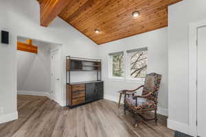Living area with baseboards, lofted ceiling with beams, wooden ceiling, and wood finished floors