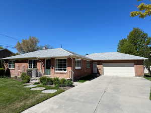 Ranch-style home featuring a front yard, brick siding, driveway, and a garage