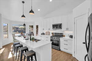 Kitchen featuring a breakfast bar area, a wealth of natural light, a sink, backsplash, and appliances with stainless steel finishes