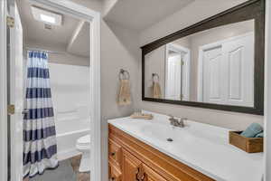 Bathroom with toilet, visible vents, vanity, and shower / bathtub combination with curtain