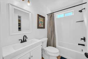 Bathroom with toilet, shower / tub combo, and vanity
