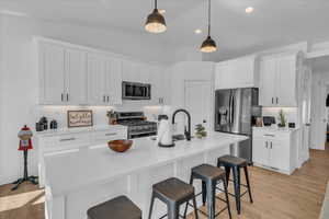 Kitchen featuring white cabinetry, decorative backsplash, appliances with stainless steel finishes, and a sink
