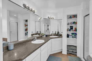 Full bath with a walk in closet, tile patterned flooring, a stall shower, and a sink