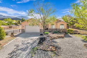 View of front facade with concrete driveway, stone siding, stucco siding, and a mountain view