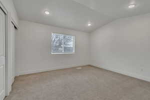 Unfurnished bedroom with vaulted ceiling, light carpet, and recessed lighting