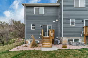Back of property featuring central air condition unit and a lawn
