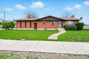 Single story home with a chimney, brick siding, and a front lawn