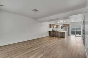 Unfurnished living room with baseboards, visible vents, and light wood-style floors