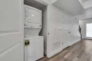 Laundry area featuring visible vents, laundry area, stacked washer / dryer, and wood finished floors