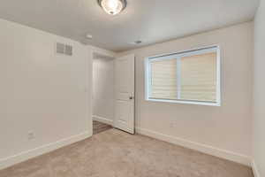 Unfurnished room with baseboards, a textured ceiling, visible vents, and light colored carpet