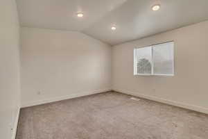 Spare room with lofted ceiling, baseboards, recessed lighting, and carpet floors
