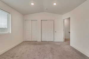 Unfurnished bedroom with carpet, recessed lighting, vaulted ceiling, two closets, and baseboards