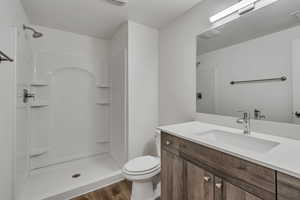 Full bath with toilet, walk in shower, and wood finished floors