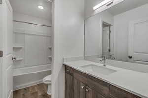 Bathroom with shower / bath combination, vanity, toilet, and wood finished floors