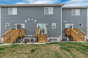 Back of property featuring central AC unit and a lawn