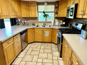 Kitchen featuring a wealth of natural light, appliances with stainless steel finishes, stone tile floors, and a sink
