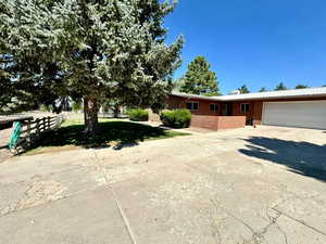 View of front facade with fence, a garage, brick siding, and driveway