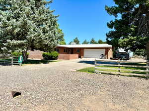 Single story home featuring fence, an attached garage, brick siding, and driveway