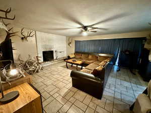 Living room with ceiling fan and a brick fireplace