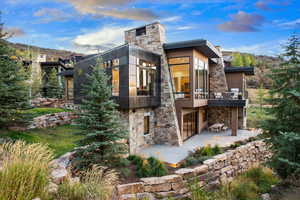 Back of house featuring a balcony, stone siding, and a patio area