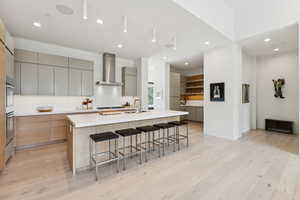 Kitchen with gray cabinetry, a breakfast bar, recessed lighting, a kitchen island with sink, and modern cabinets