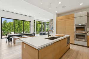 Kitchen with light brown cabinets, modern cabinets, appliances with stainless steel finishes, light wood finished floors, and recessed lighting