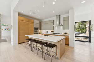 Kitchen with a breakfast bar area, modern cabinets, light wood-style flooring, a kitchen island with sink, and recessed lighting