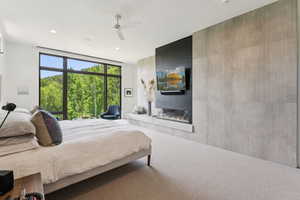 Carpeted bedroom with a large fireplace, recessed lighting, and ceiling fan