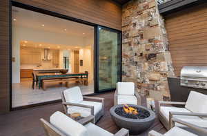 View of patio featuring a wooden deck, a fire pit, and an outdoor kitchen