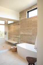 Full bathroom featuring a soaking tub, tile walls, and tiled shower