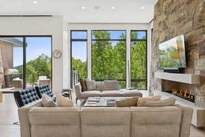 Living room with wood finished floors, a stone fireplace, and recessed lighting