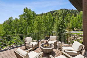Wooden deck with a forest view and an outdoor living space with a fire pit