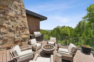 Wooden deck with an outdoor living space with a fire pit and an outdoor kitchen